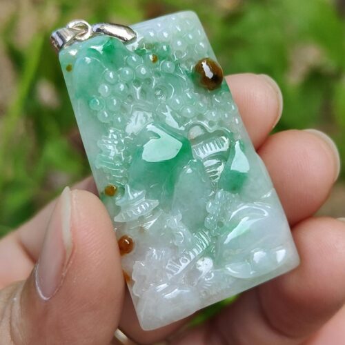a hand holding a jade pendant