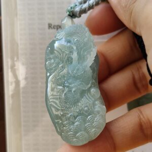 a hand holding a jade pendant