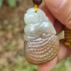 une main tenant un pendentif en jade