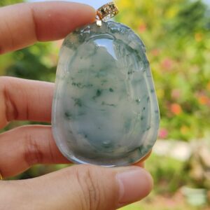 uma mão segurando um pingente de jade