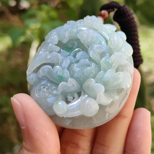 một bàn tay cầm một mặt dây chuyền ngọc bích