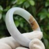 a hand wearing glove holding a white ring