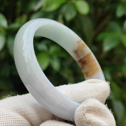 a hand wearing glove holding a white ring