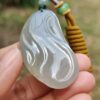 a hand holding a jade pendant