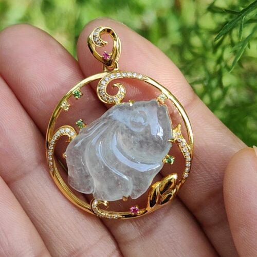 a hand holding a gold pendant with a fish in it