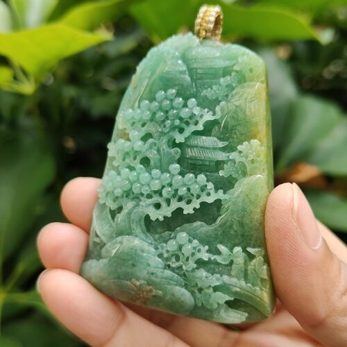 a hand holding a jade pendant