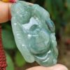 a hand holding a jade pendant