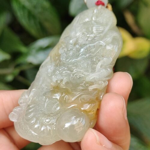 a hand holding a jade pendant