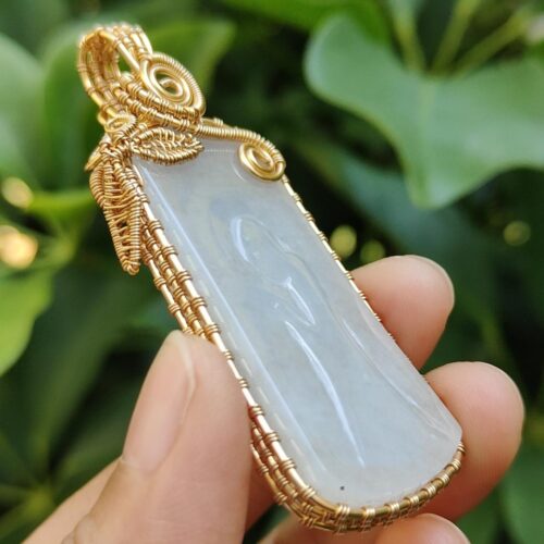 एक हाथ में जेड पेंडेंट थामे हुए