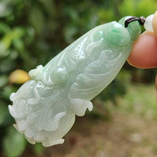 a hand holding a jade pendant