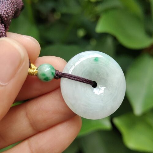 une main tenant un pendentif en jade