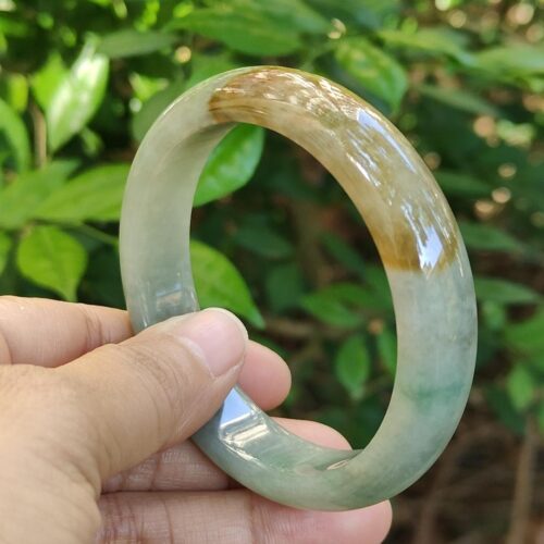 a hand holding a round green and brown bracelet