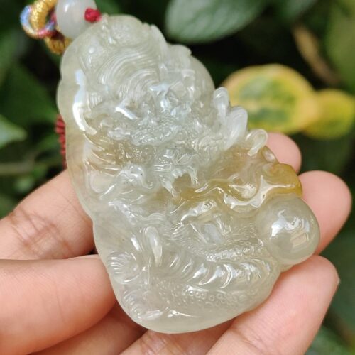 a hand holding a jade pendant