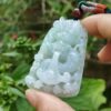 une main tenant un pendentif en jade