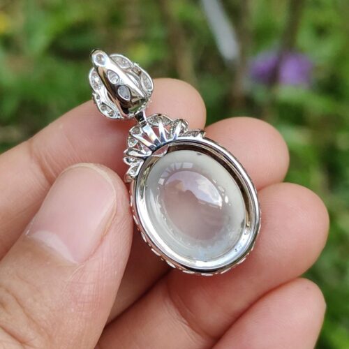 a hand holding a silver pendant