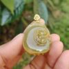a hand holding a jade pendant
