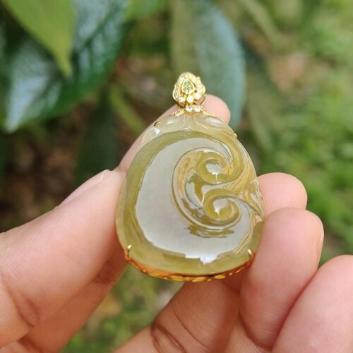 a hand holding a jade pendant