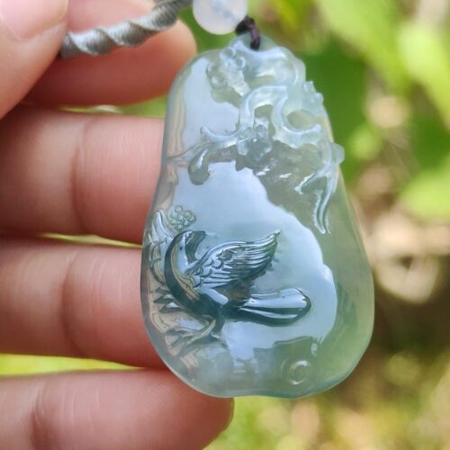 a hand holding a jade pendant