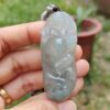 une main tenant un pendentif en jade