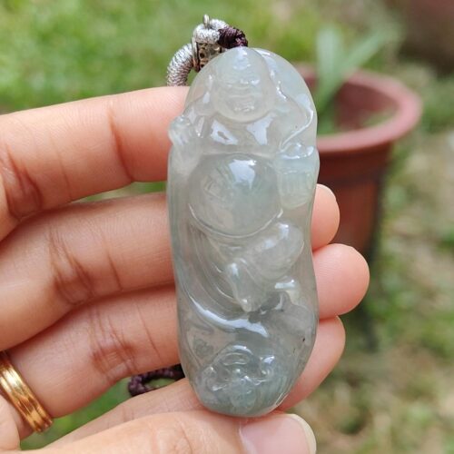 une main tenant un pendentif en jade