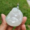 a hand holding a jade pendant