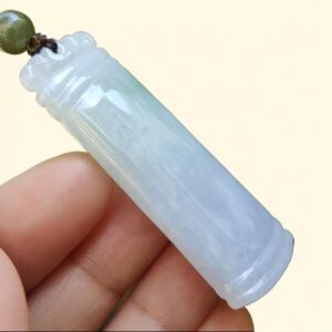 a hand holding a jade pendant