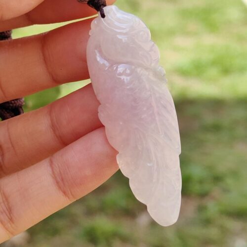 a hand holding a white and pink pendant