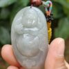 a hand holding a jade pendant