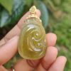 a hand holding a jade pendant