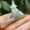 a hand holding a small jade statue