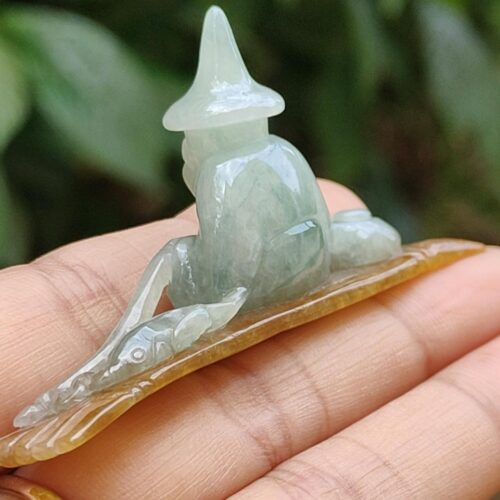 a hand holding a small jade statue