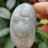 a hand holding a jade pendant