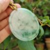 a hand holding a jade pendant