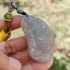 a hand holding a jade pendant