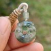 a hand holding a jade pendant