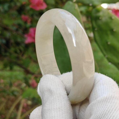 a hand in glove holding a white ring