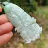 a hand holding a jade pendant