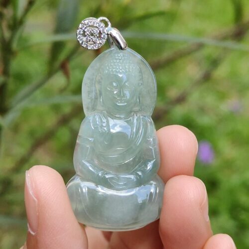a hand holding a jade buddha pendant