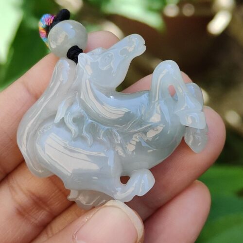 a hand holding a jade horse pendant