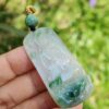 a hand holding a jade pendant