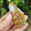 une main tenant un pendentif en jade