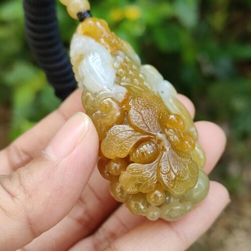 une main tenant un pendentif en jade