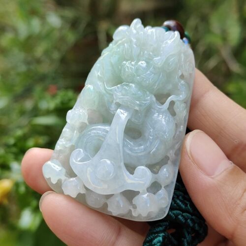 une main tenant un pendentif en jade