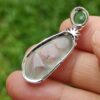 a hand holding a silver pendant