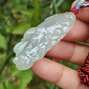a hand holding a jade pendant