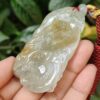 a hand holding a jade pendant