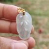 Una mano sosteniendo un colgante de jade blanco.