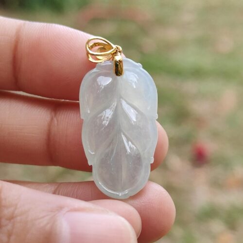 Una mano sosteniendo un colgante de jade blanco.