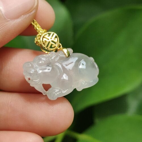 một bàn tay cầm một mặt dây chuyền ngọc bích