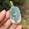 a hand holding a jade pendant